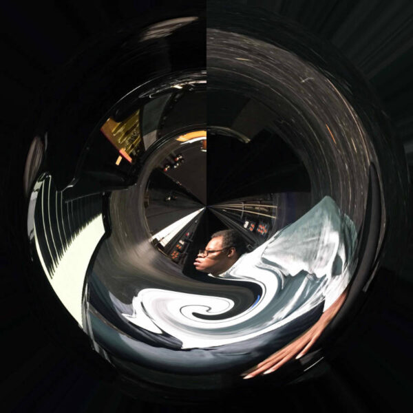 Photo manipulation of Matt Shipp playing piano in a circle mirror reflection